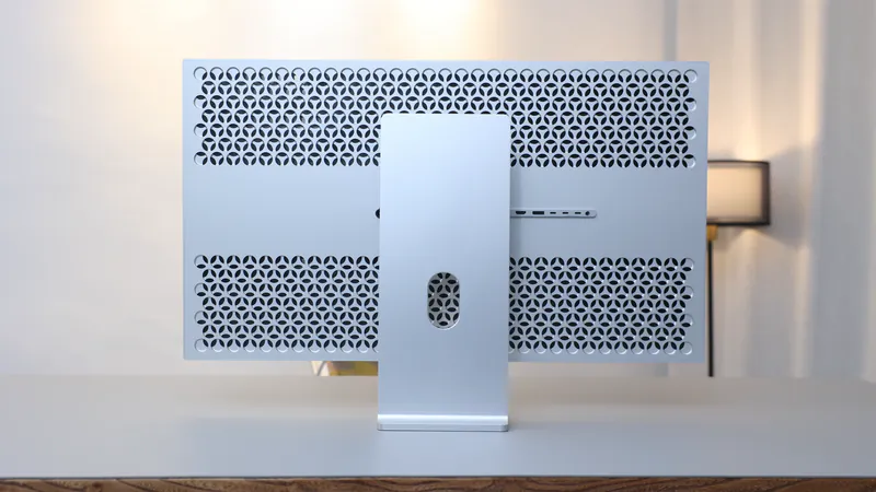 Perforierte Rückseite des Monitors Kuycon G32P auf einem Schreibtisch, mit silbernem Standfuß und Anschlussleiste